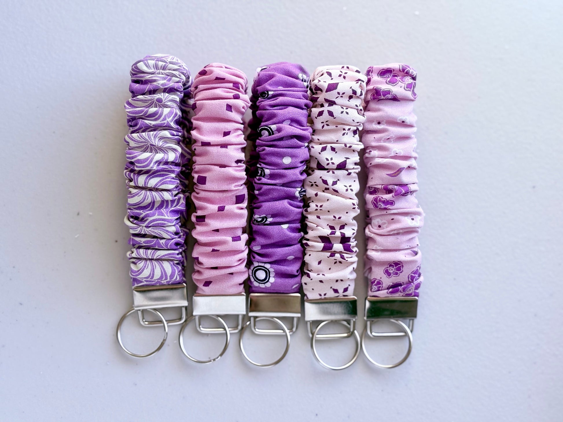 Set of five purple and white patterned keychains on a light gray background