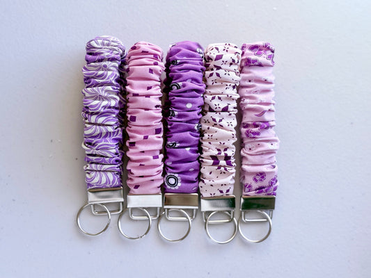Set of five purple and white patterned keychains on a light gray background